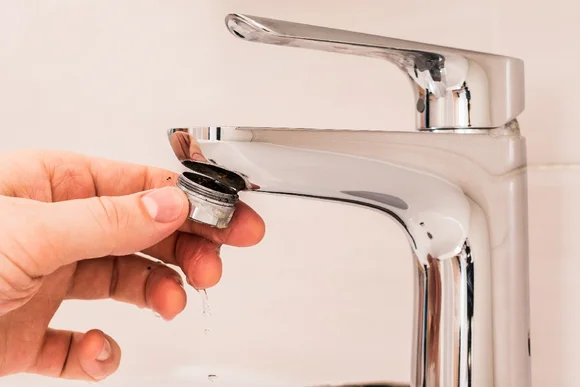 Person hält verkalkten Wasserhahn-Sieb